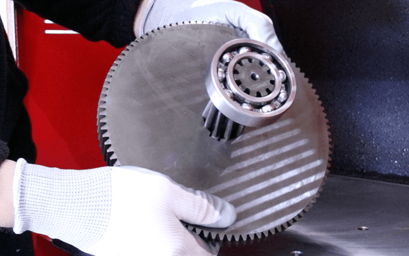 Load image into Gallery viewer, Operator holding a large gear with internal keyway and bearing assembly produced on the Nargesa BM25 broaching machine