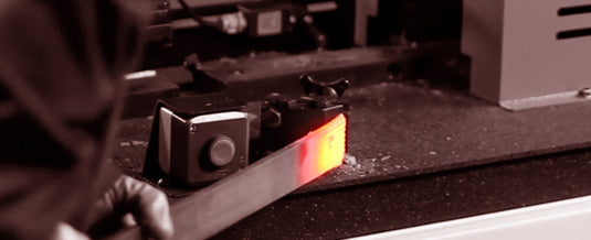 Heated steel bar being positioned in the Nargesa PC16 forging station