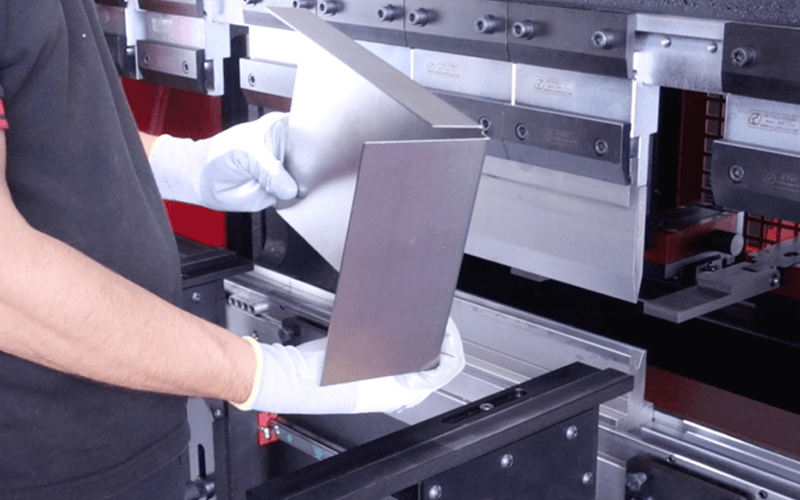 Load image into Gallery viewer, Operator inspecting a multi-bend sheet metal part after forming on the Nargesa MP1500CNC press brake
