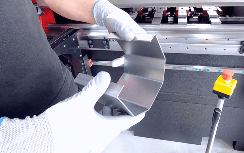 Load image into Gallery viewer, Operator holding a precision-bent metal component produced on the Nargesa MP1500CNC press brake
