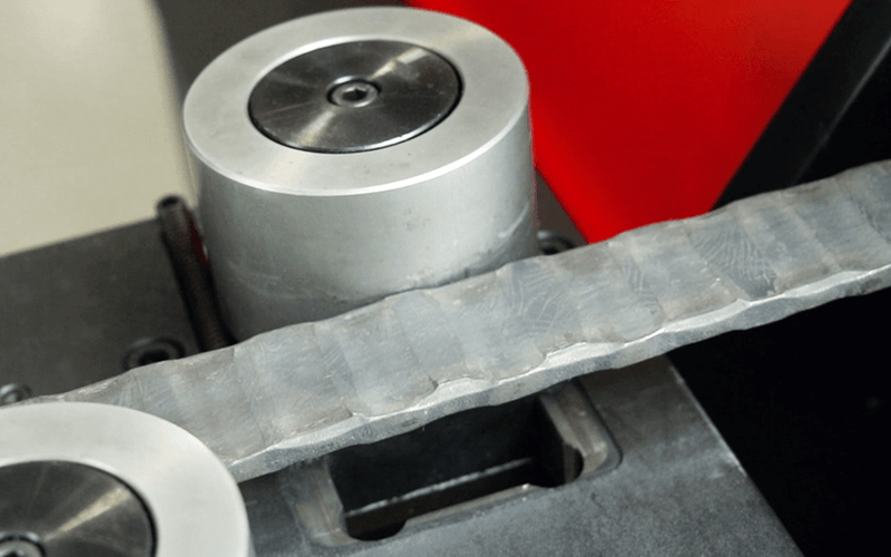 Load image into Gallery viewer, Close-up of the Nargesa NOA60 embossing rollers forming a decorative pattern in steel
