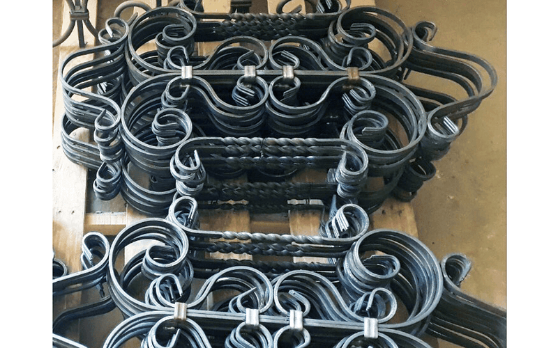 Load image into Gallery viewer, Stacked ornamental railing components with twisted bars and scrolls produced on the Nargesa MT150A
