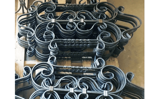 Stacked ornamental railing components with twisted bars and scrolls produced on the Nargesa MT150A