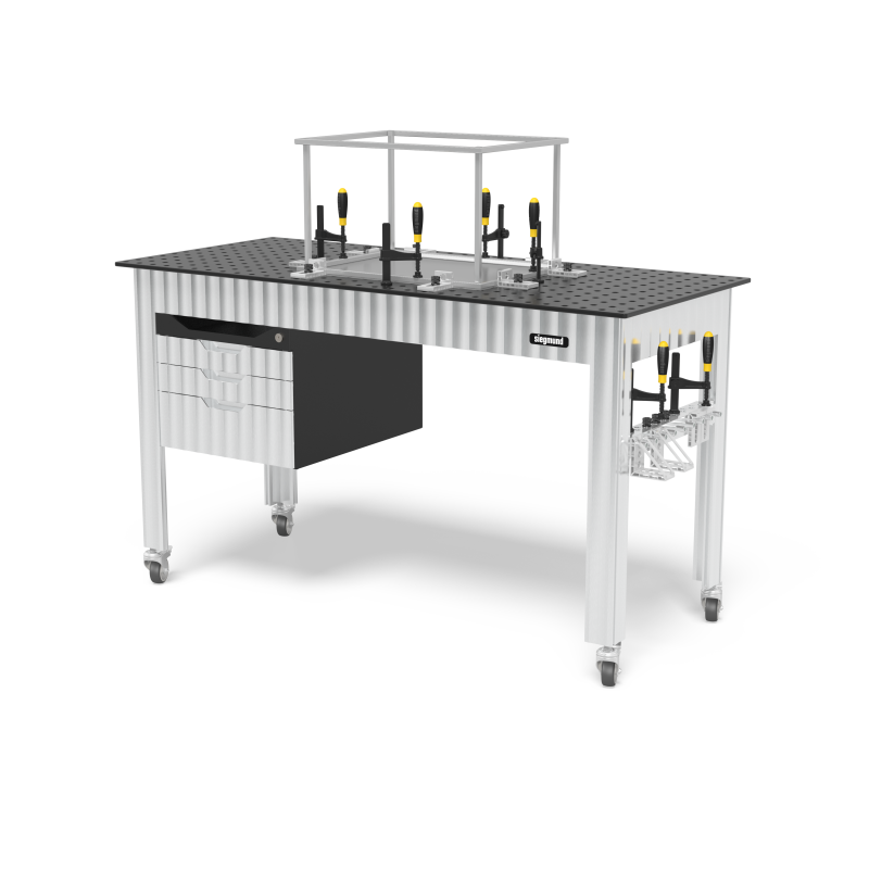 Load image into Gallery viewer, Siegmund welding table on casters with a perforated top, clamps and stops on the surface, a drawer cabinet on the left, a tool rack on the right leg, and an overhead frame above the table.
