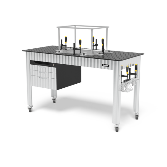 Siegmund welding table on casters with a perforated top, clamps and stops on the surface, a drawer cabinet on the left, a tool rack on the right leg, and an overhead frame above the table.